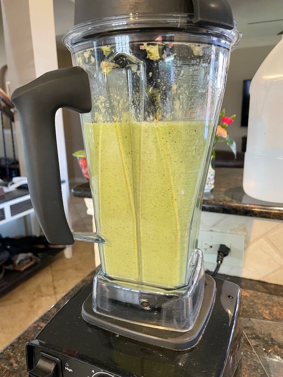 A Vitamix blender holding a minty green concoction.